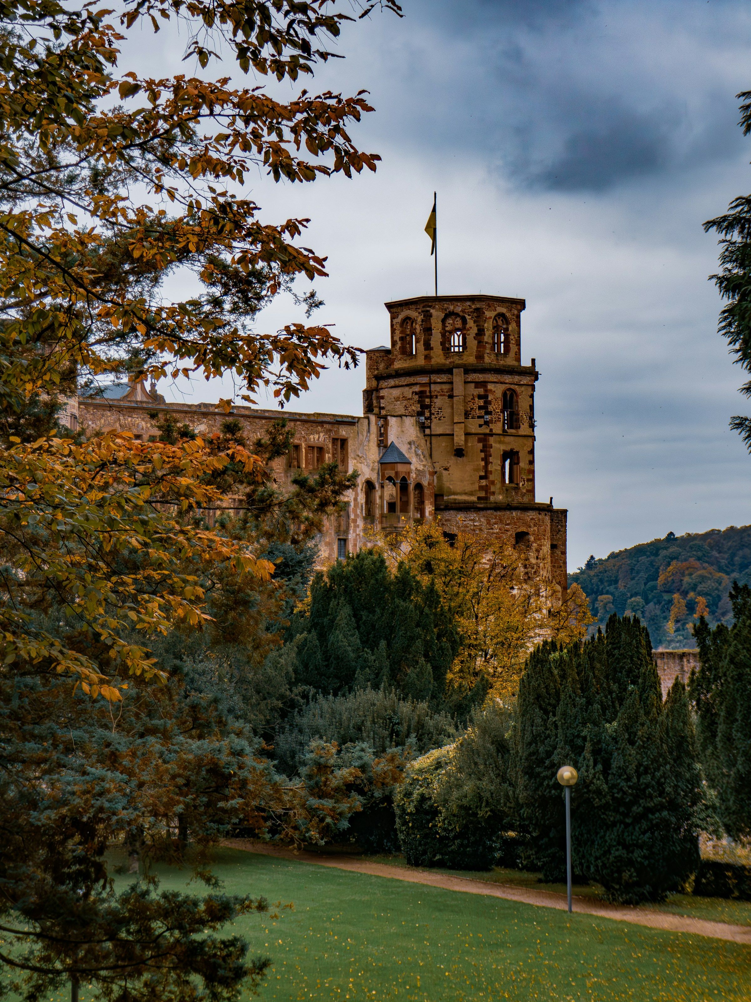 Turm des Heidelberger Schlosses zwischen Bäumen mit herbstlich gefärbtem Laub