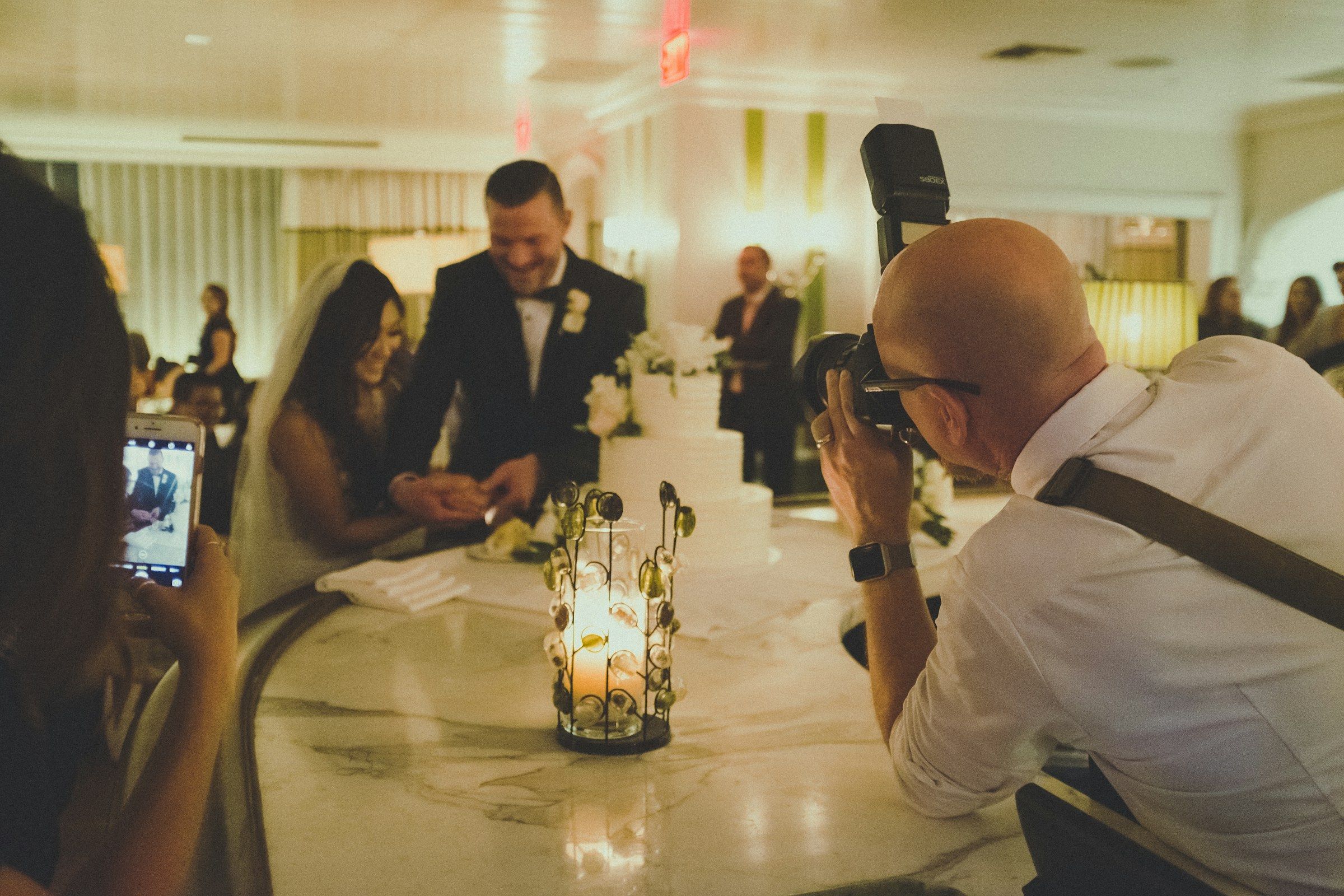 Ein Fotograf fotografiert ein Brautpaar beim Unterschreiben an einem Tisch mit Kerzenlicht